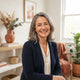 A professional portrait of a smiling woman in a bright, modern home setting with warm terracotta and burnt sienna decor.